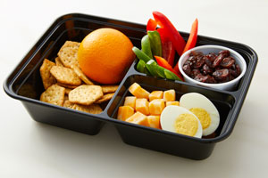 Bento box with cheese cubes, crackers, egg, orange, peppers and raisins