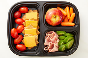 Bento Box with cracker cuts, tomatoes, apple, carrots, cucumber and ham