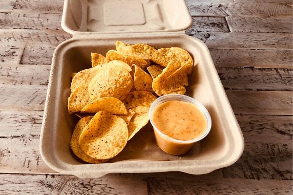 Land O'Lakes Foodservice Chipotle Queso with Corn Chips served in a to-go container