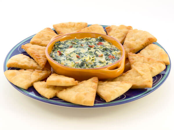 Bowl of spinach artichoke dip with pita bread pieces