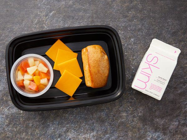Land O’Lakes Foodservice | Fruit salad, cracker cuts, and roll bento box with skim milk on the side